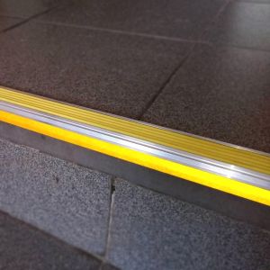 Тактильно-контрастна жовта стрічка у алюмінієвому кутовому профілі зі світловідбиваючою смугою